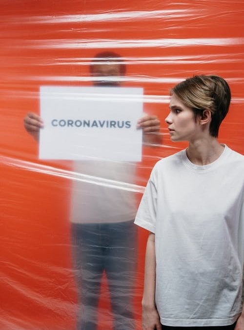 woman with sign saying coronavirus in background