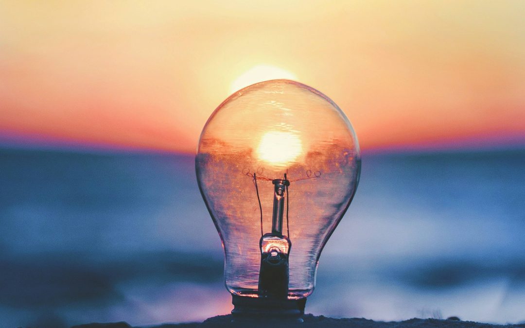 Light bulb in sand with sea and sand in background
